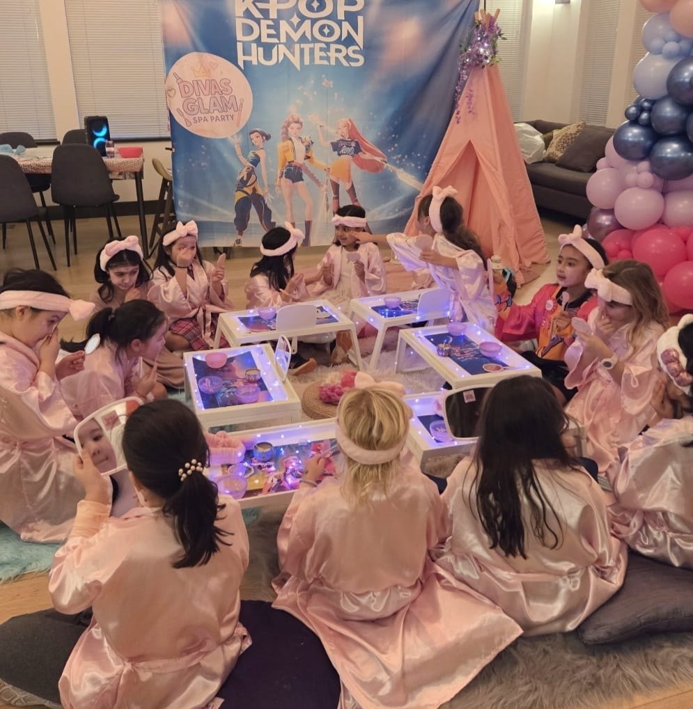 Top-down view of girls around Divas Glam Spa trays with balloon arch